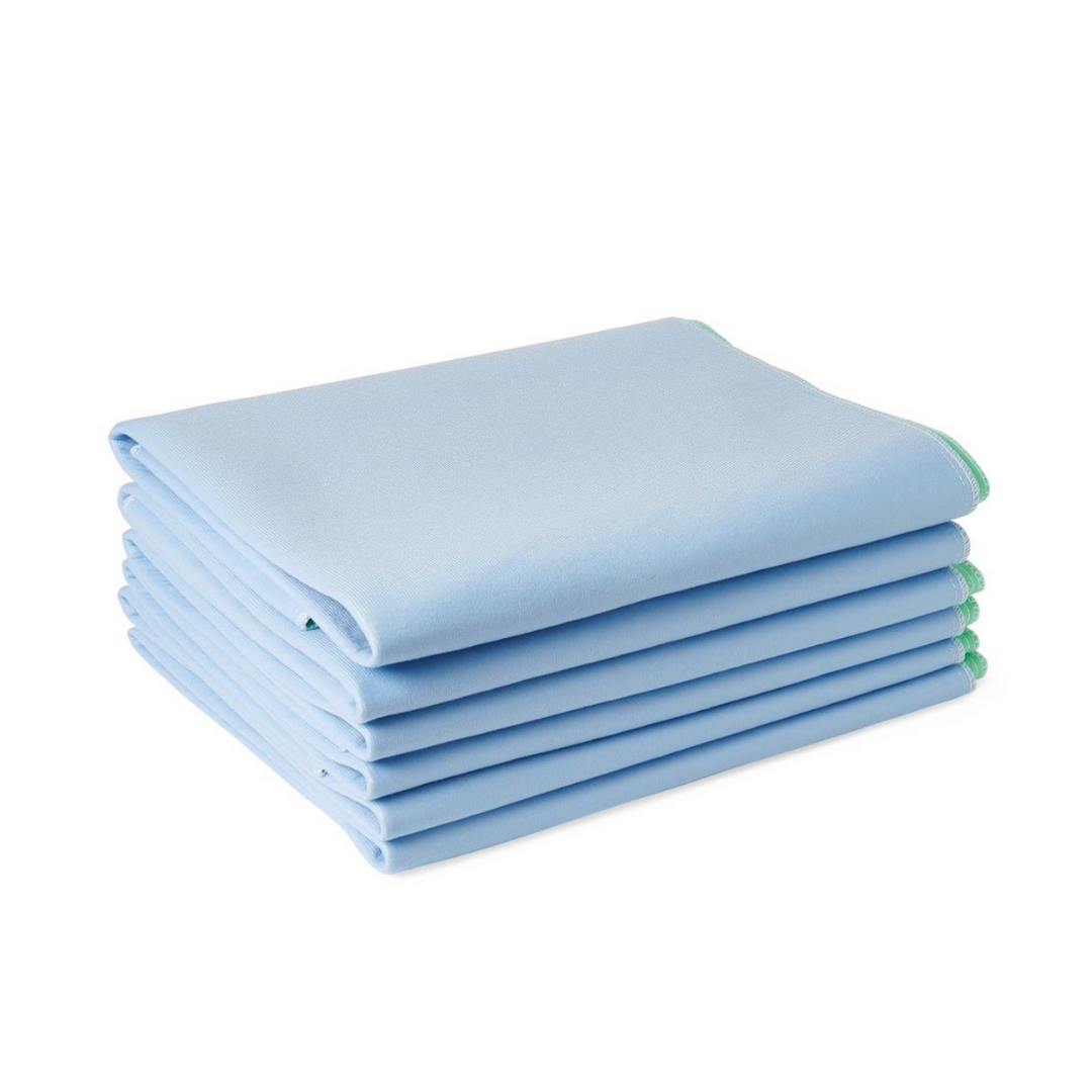 A stack of six Medline Quick Dry Poly Laminated Reusable Underpads, 34 x 36, light blue with green trim, made from an advanced fiber blend for softness, is neatly arranged on a white background.